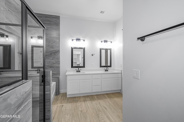 bathroom with hardwood / wood-style flooring, vanity, and a shower with door