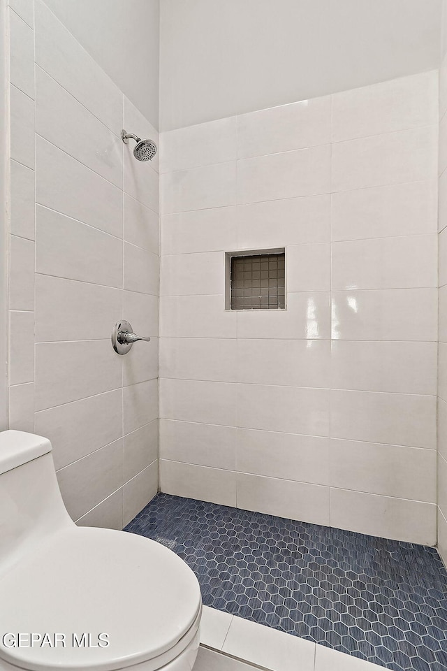 bathroom featuring tiled shower and toilet