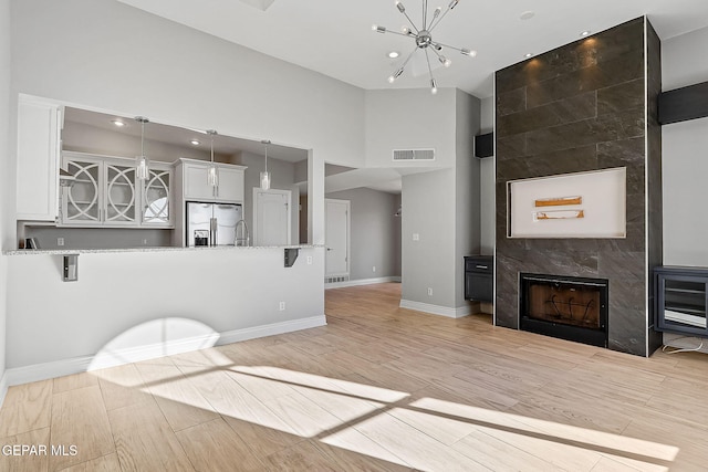 kitchen with white cabinetry, hanging light fixtures, a kitchen bar, stainless steel fridge with ice dispenser, and kitchen peninsula