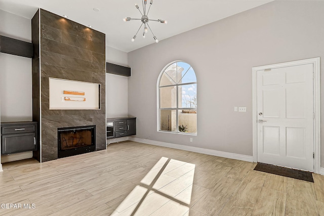 unfurnished living room featuring a tiled fireplace and a chandelier