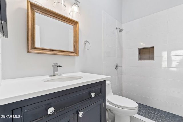 bathroom with vanity, a tile shower, and toilet