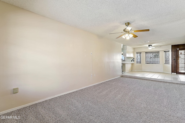 spare room featuring ceiling fan, light colored carpet, and a textured ceiling