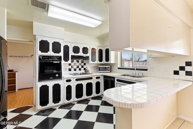 kitchen featuring tile countertops, black appliances, sink, backsplash, and kitchen peninsula