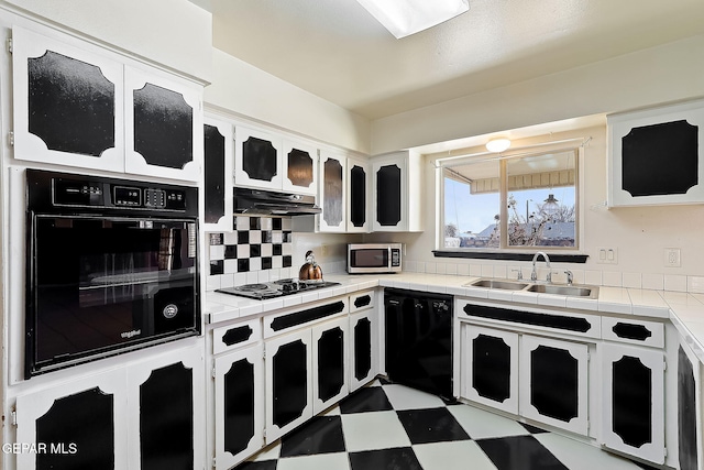 kitchen featuring sink, white cabinetry, tile counters, decorative backsplash, and black appliances