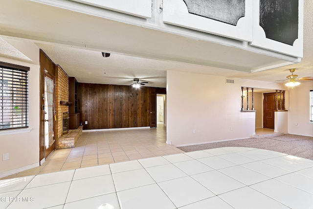 tiled spare room featuring a textured ceiling, ceiling fan, and wood walls