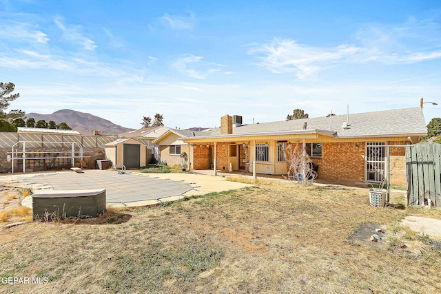 rear view of house with a mountain view, a patio, and a storage unit