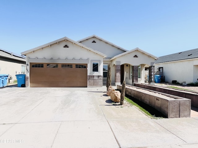 view of front of home with stucco siding, concrete driveway, and an attached garage