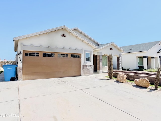 view of front facade featuring a garage, driveway, and stucco siding