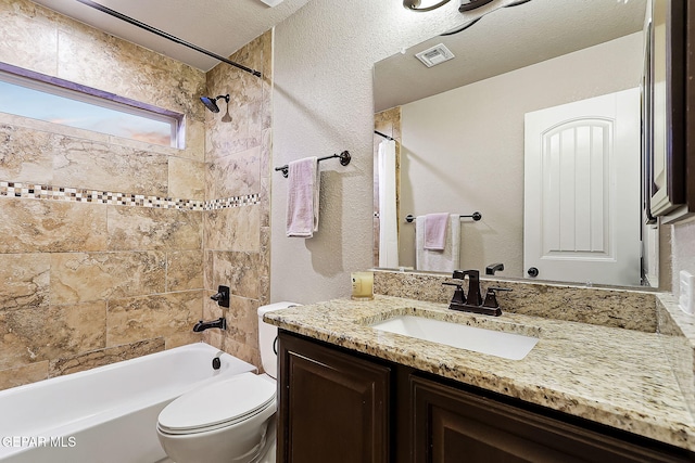 full bathroom with tiled shower / bath combo, vanity, a textured ceiling, and toilet