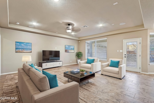 living room featuring a tray ceiling and ceiling fan