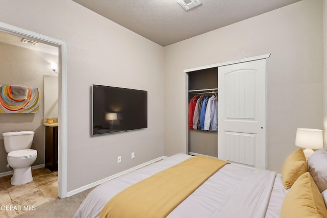 bedroom featuring ensuite bath, a closet, and a textured ceiling