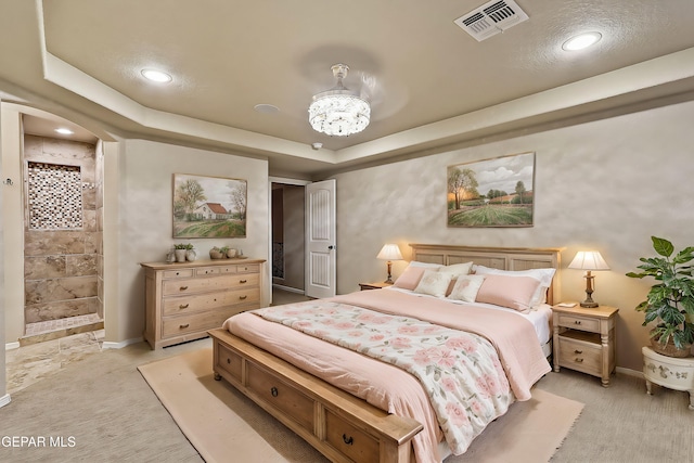 carpeted bedroom featuring a tray ceiling and a notable chandelier