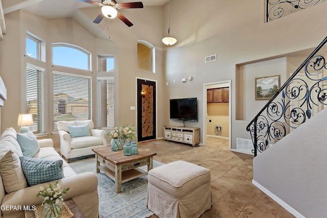 living room with a towering ceiling, light tile patterned floors, and ceiling fan