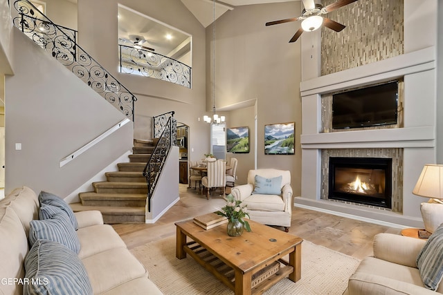 living room featuring a tiled fireplace, ceiling fan with notable chandelier, and light hardwood / wood-style floors