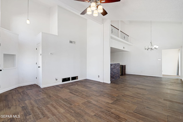 unfurnished living room featuring high vaulted ceiling, dark hardwood / wood-style floors, ceiling fan with notable chandelier, and a textured ceiling