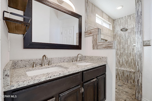 bathroom featuring tiled shower and vanity