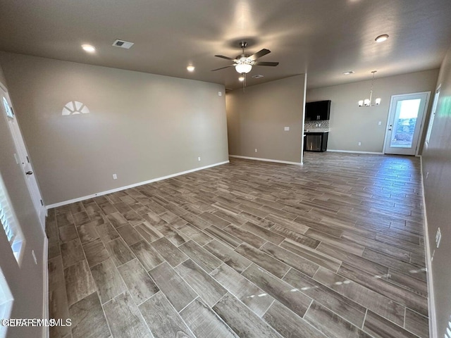 unfurnished living room featuring ceiling fan with notable chandelier