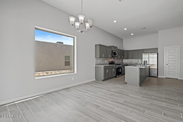 kitchen with gray cabinetry, decorative light fixtures, an island with sink, stainless steel appliances, and backsplash