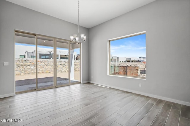 empty room with a notable chandelier, plenty of natural light, and wood-type flooring