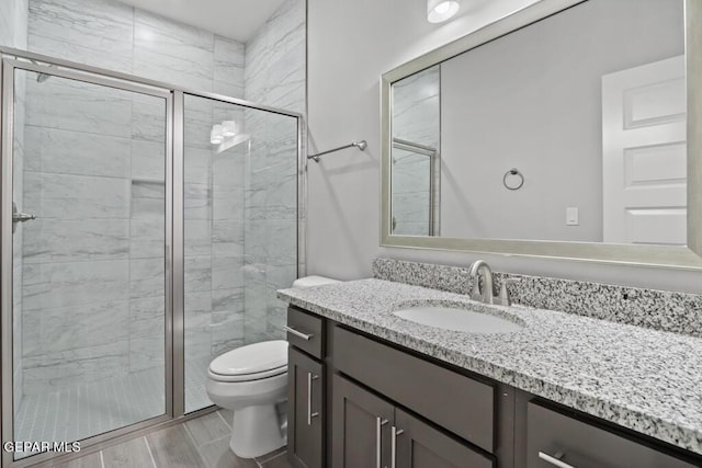 bathroom featuring vanity, a shower with shower door, and toilet