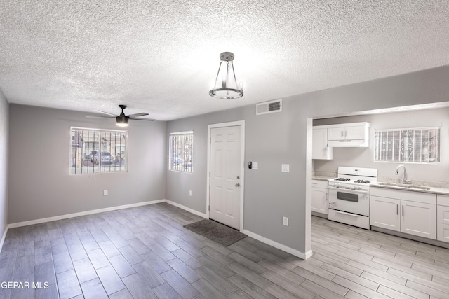 kitchen featuring sink, pendant lighting, white gas stove, and white cabinets