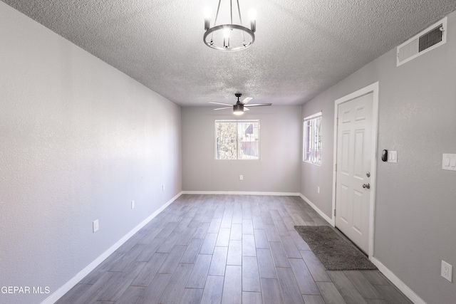 interior space featuring a textured ceiling, hardwood / wood-style floors, and ceiling fan with notable chandelier