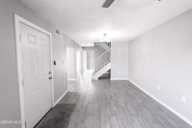 interior space with a textured ceiling, a chandelier, and light hardwood / wood-style flooring