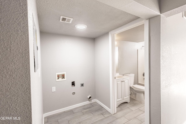 clothes washing area with hookup for a washing machine, gas dryer hookup, a textured ceiling, and electric dryer hookup