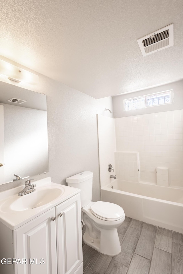 full bathroom with a textured ceiling, toilet,  shower combination, and vanity