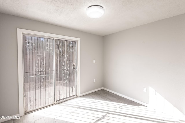 unfurnished room with hardwood / wood-style flooring and a textured ceiling