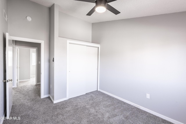 unfurnished bedroom with carpet floors, a closet, a textured ceiling, and ceiling fan