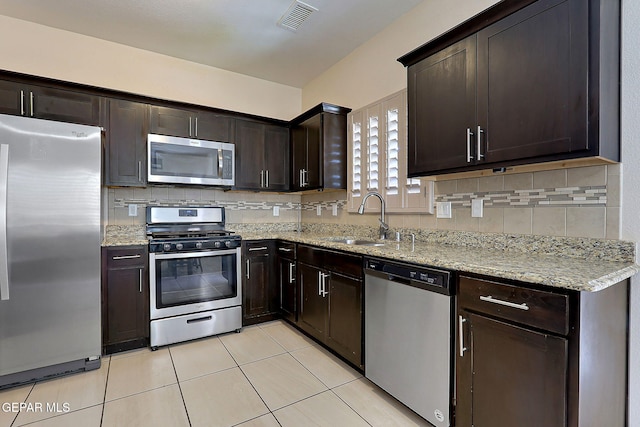 kitchen featuring sink, light tile patterned floors, dark brown cabinets, and appliances with stainless steel finishes