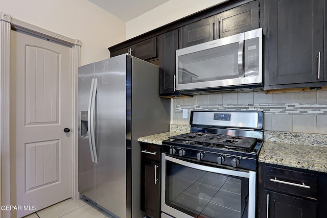 kitchen featuring light tile patterned flooring, appliances with stainless steel finishes, light stone countertops, and backsplash