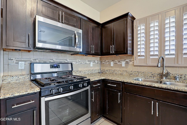 kitchen with appliances with stainless steel finishes, tasteful backsplash, sink, light stone counters, and dark brown cabinetry