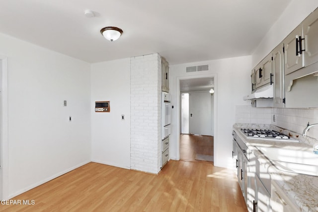 kitchen featuring sink, gray cabinetry, decorative backsplash, light hardwood / wood-style floors, and white oven