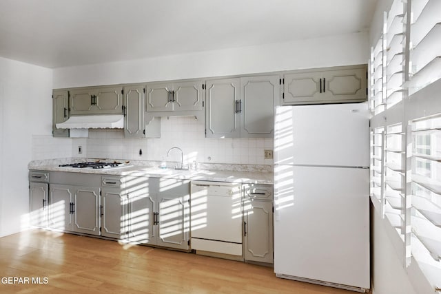 kitchen featuring white appliances, light hardwood / wood-style floors, sink, and decorative backsplash