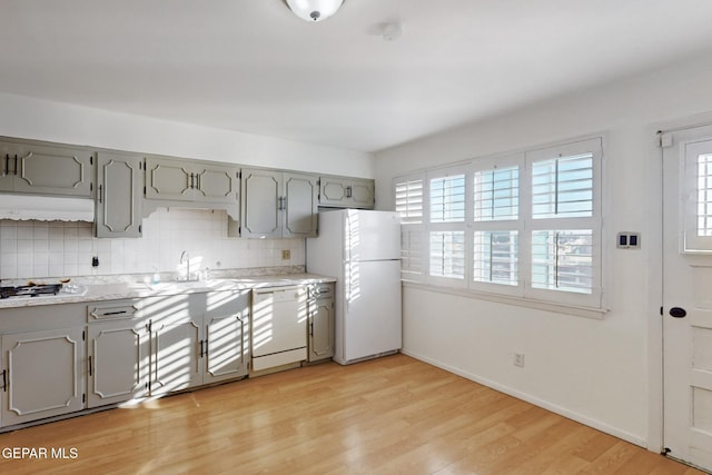 kitchen featuring gray cabinets, sink, backsplash, white appliances, and light wood-type flooring