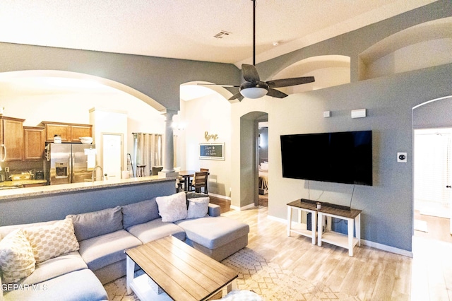 living room featuring light hardwood / wood-style flooring, ceiling fan, and ornate columns