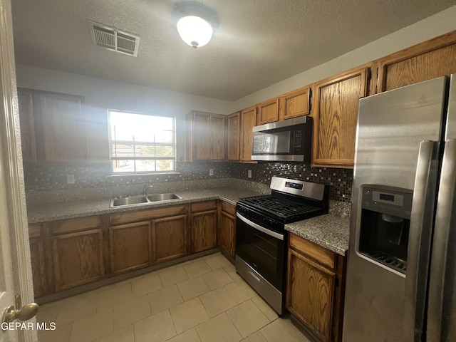 kitchen featuring stainless steel appliances, sink, a textured ceiling, and backsplash