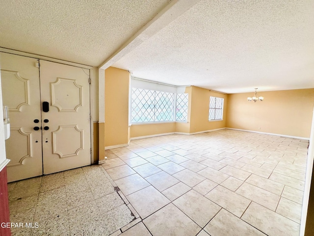 entryway with a textured ceiling and a notable chandelier