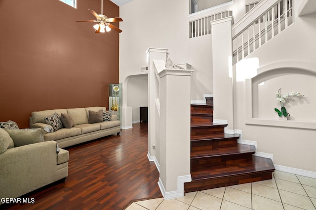 stairway with a high ceiling, wood-type flooring, and ceiling fan