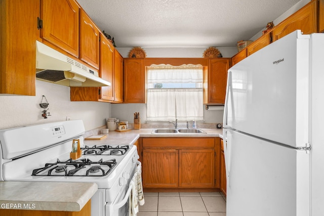 kitchen with sink, white appliances, light tile patterned floors, and a textured ceiling