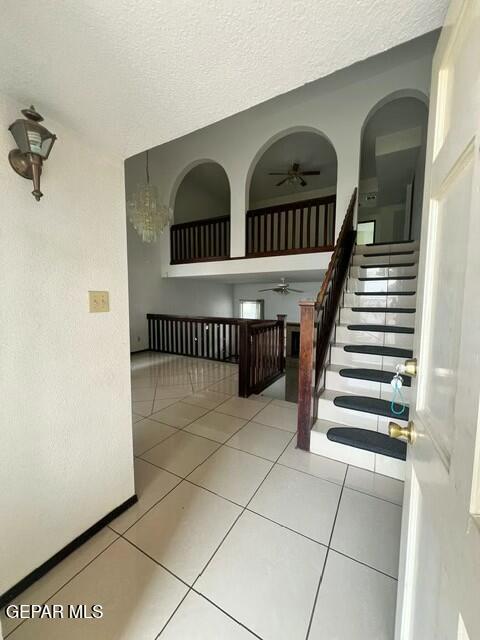 interior space featuring ceiling fan, a textured ceiling, and light tile patterned floors