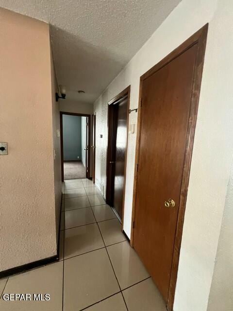 hallway with light tile patterned floors and a textured ceiling