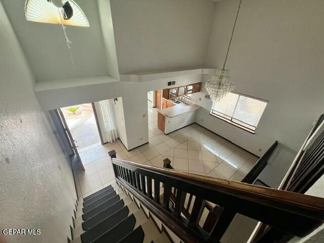 stairs featuring a chandelier, tile patterned flooring, and a high ceiling