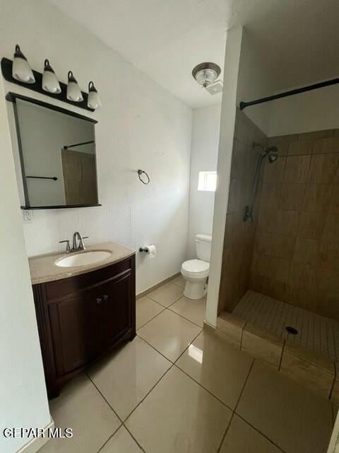 bathroom featuring vanity, toilet, tile patterned flooring, and a tile shower