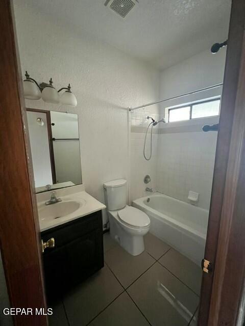 full bathroom featuring vanity, toilet, tiled shower / bath combo, and tile patterned flooring