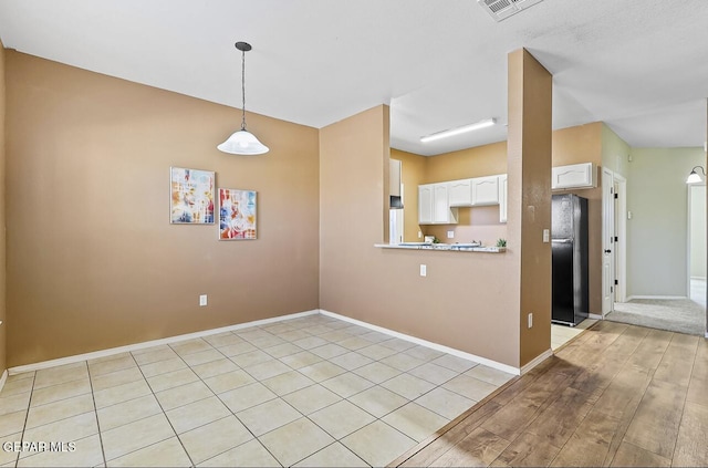 kitchen with black refrigerator, pendant lighting, white cabinets, and kitchen peninsula