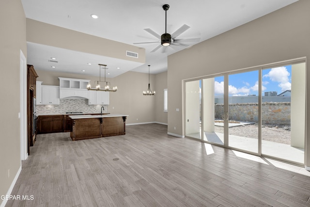 kitchen with sink, a kitchen island with sink, plenty of natural light, light hardwood / wood-style floors, and decorative light fixtures