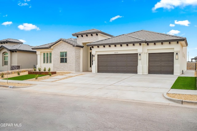 prairie-style home featuring a tile roof, concrete driveway, a garage, and stucco siding